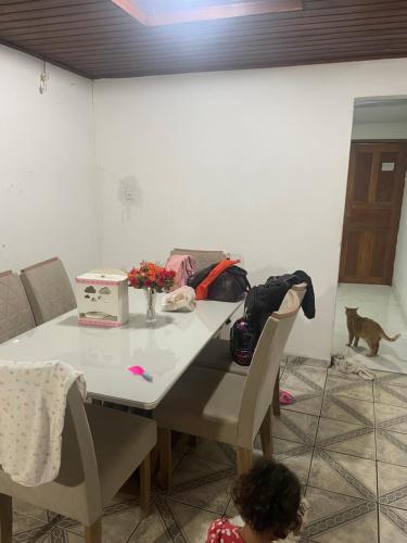 a table and chairs with a cat in a room at Casa Queiroz in Ananindeua