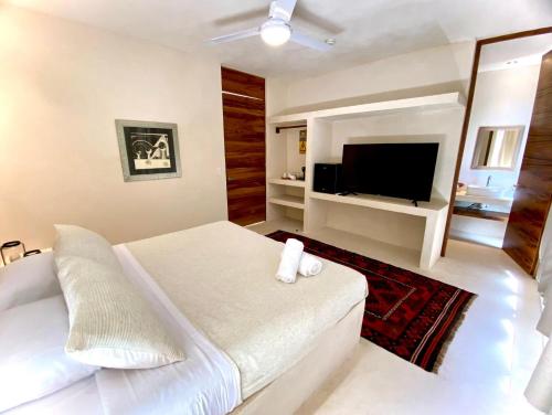 a white bedroom with a large bed and a flat screen tv at Cocuna Boutique Suites La Manzanilla Jalisco in La Manzanilla