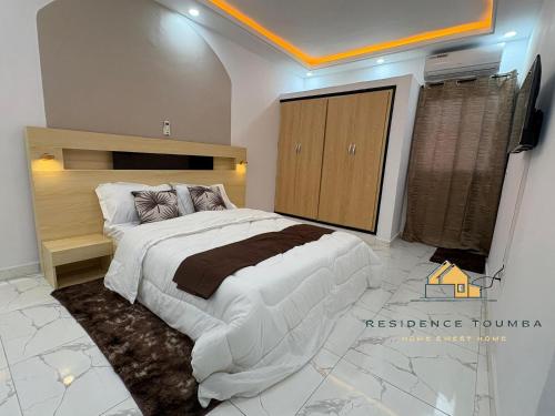 una camera da letto con un grande letto bianco e una televisione di luxury a Abidjan