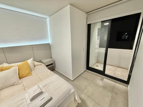 ein Schlafzimmer mit einem weißen Bett und einem großen Fenster in der Unterkunft Petit Premium Nueva Cba - Oulton in Cordoba