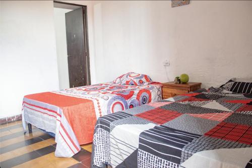 a bedroom with two beds with colorful blankets at Hostal Los Milagros in Santa Ana