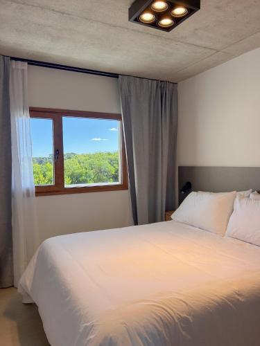a bedroom with a white bed and a window at Jade Residencias de Mar in Villa Gesell
