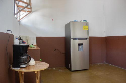 a kitchen with a stainless steel refrigerator and a table at Hostal Los Milagros in Santa Ana