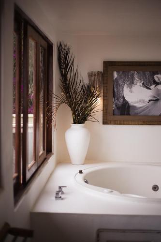 a bathroom with a white tub and a plant in a vase at Beijo do Vento Pousada in Arraial d'Ajuda