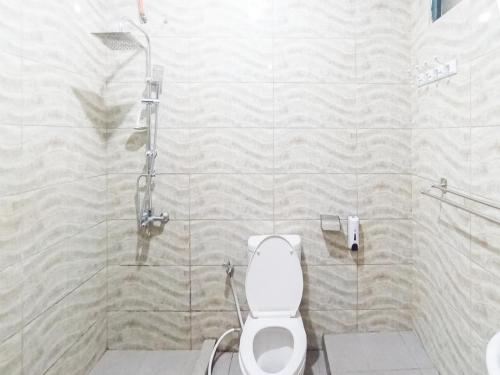 a bathroom with a shower and a white toilet at Gatsu Resort RedPartner at Karangploso in Karangploso