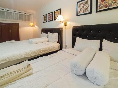 two beds in a room with white sheets and pillows at Gatsu Resort RedPartner at Karangploso in Karangploso