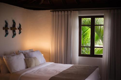 a bedroom with a white bed and a window at Beijo do Vento Pousada in Arraial d'Ajuda