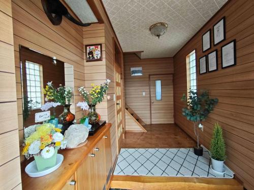 a room with wood paneled walls and a hallway with flowers at kitagunihouse noboribetsu in Noboribetsu