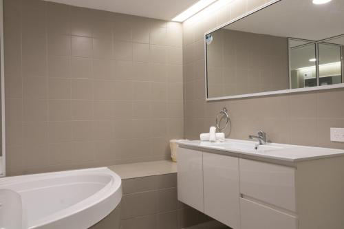 Un baño blanco con lavabo y espejo. en Silver Sands Resort Mandurah, en Mandurah