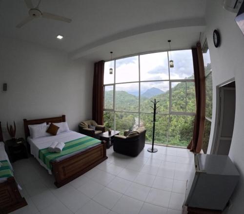 a bedroom with a bed and a large window at Villa Rivora in Kitulgala