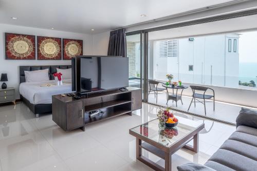 a living room with a large television and a bed at Tropical Sea View Residence in Lamai