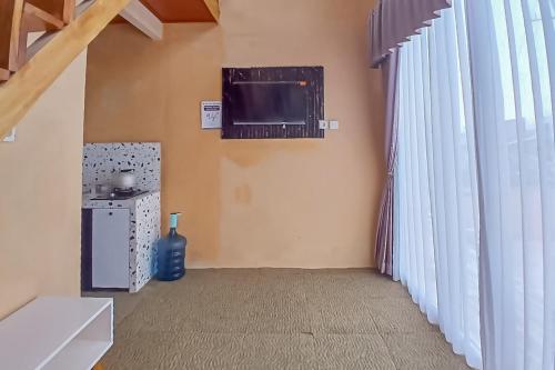 a living room with a tv and a window at Danin Villa Syariah Dieng Mitra RedDoorz in Dieng