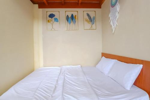 a white bed in a room with pictures on the wall at Danin Villa Syariah Dieng Mitra RedDoorz in Dieng
