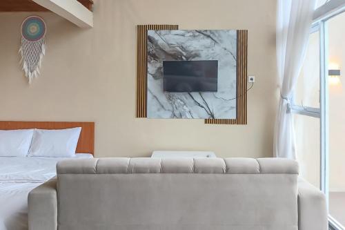 a bedroom with a couch and a tv on the wall at Danin Villa Syariah Dieng Mitra RedDoorz in Dieng