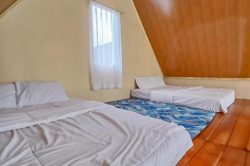 a room with two beds and a window at Danin Villa Syariah Dieng Mitra RedDoorz in Dieng