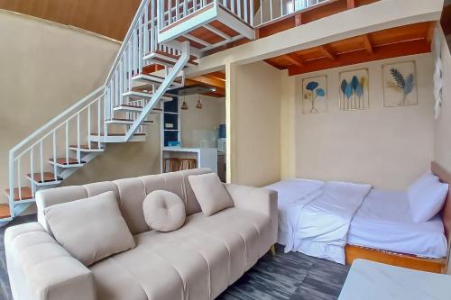 a living room with a couch and a staircase at Danin Villa Syariah Dieng Mitra RedDoorz in Dieng