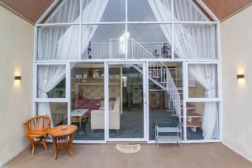 a living room with a large window and a table and chairs at Danin Villa Syariah Dieng Mitra RedDoorz in Dieng