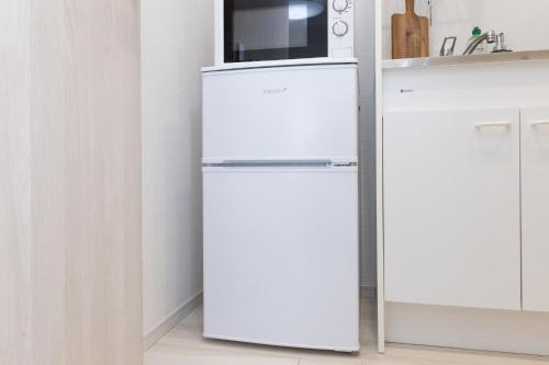 a white refrigerator with a microwave on top of it at メルディア東堀切 in Tokyo