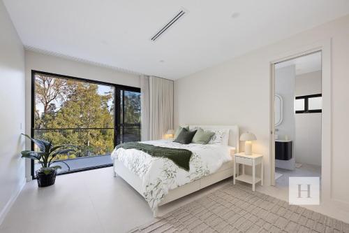 a white bedroom with a bed and a large window at Sunset and Serenity Trinity in Morisset East