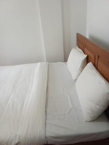 a bed with white sheets and pillows in a room at Glenfalls Residencies in Nuwara Eliya
