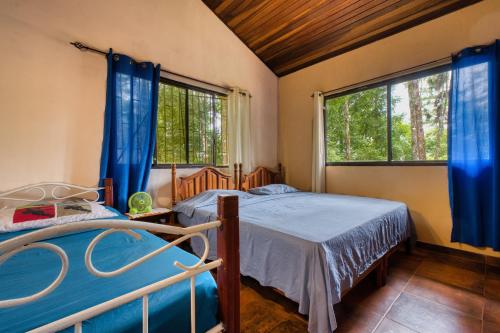 a bedroom with two beds and two windows at Casa Naranja en Cerro Azul in Cerro Azul
