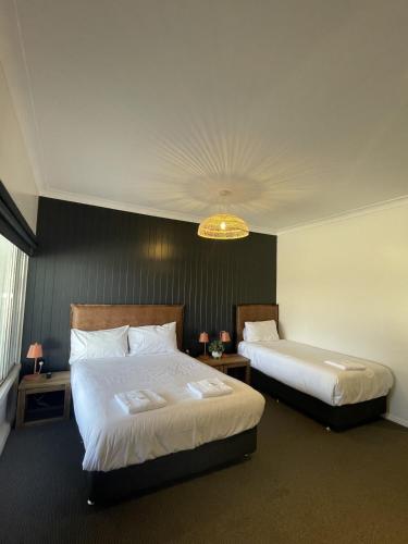 a hotel room with two beds and a chandelier at Palm and Pawn Motor Inn in Wagga Wagga