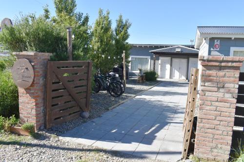 a wooden gate with a brick fence and a sidewalk at Hotel Cabañas Aparts Tierra de Glaciares in El Calafate