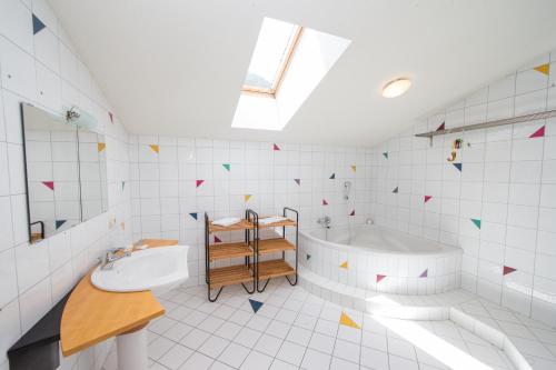Baño blanco con bañera y lavamanos en Apartments Schmittental - Schmitten62 Self Check-In, en Zell am See