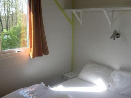 a bed in a room with a window and a white bed sidx sidx at Mobil home confortable avec terrasse en Charente-Maritime - API-1-52-690 in Le Fouilloux