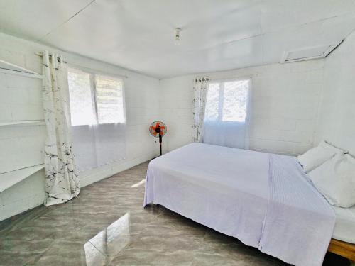 a bedroom with a white bed and two windows at Pearl Cottage - 2 Bedroom Entire Place in Nuku‘alofa