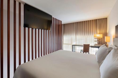 a bedroom with a large white bed and a desk at Crowne Plaza Vilamoura - Algarve by IHG in Vilamoura