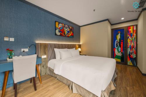 a bedroom with a large white bed and a desk at Solare De Monte Hotel & Spa in Hanoi