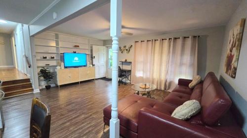 a living room with a couch and a television at Irie Villa GameRoom Kids&PetFriendly CharcoalGrill in Fayetteville