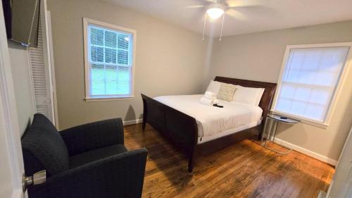 a bedroom with a bed and a chair and two windows at Irie Villa GameRoom Kids&PetFriendly CharcoalGrill in Fayetteville