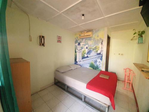 a small bedroom with a bed with a red blanket at Ki Agung Prestise Hotel in Timuran