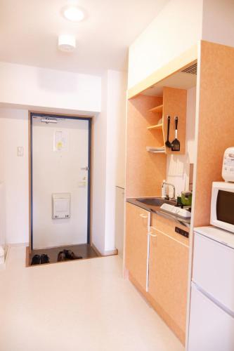 a small kitchen with a refrigerator and a microwave at G62 駅徒歩3分 おしゃれで可愛い 4人可能 3 minutes walk from the station Nagoya駅から1駅 in Nagoya