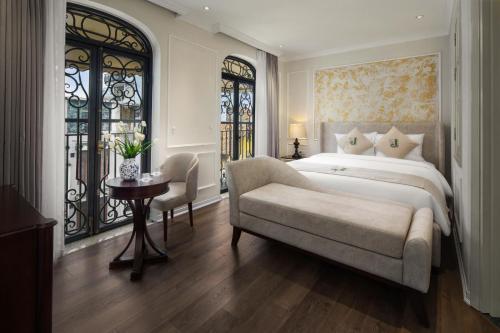 a bedroom with a bed and a chair and a table at Jade Boutique Hotel in Hanoi