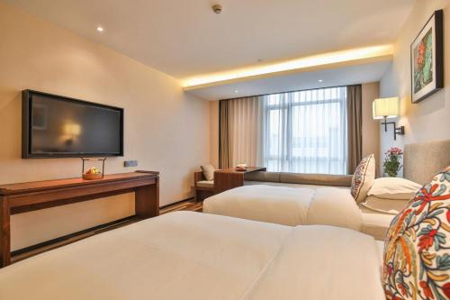 a hotel room with two beds and a flat screen tv at SSAW Boutique Hotel Qidong Tiansheng in Qidong