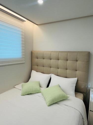 a bedroom with a large bed with two green pillows at Shiny Picnic in Seoul