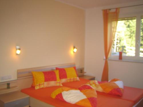 Schlafzimmer mit einem Bett mit bunten Kissen und einem Fenster in der Unterkunft Apart Raphael in Niederthai