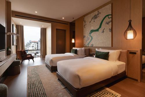 a hotel room with two beds and a television at SOMA HOTEL Riverside in Phnom Penh