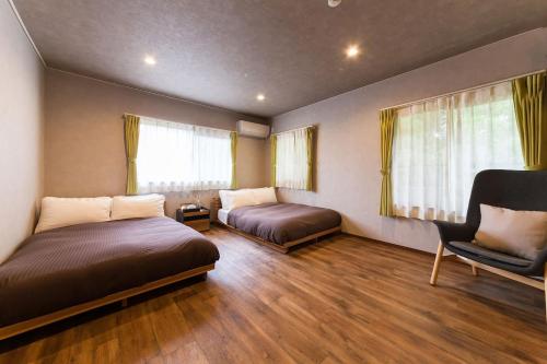 a bedroom with two beds and a chair at Ise Shima Moritoumi in Shima