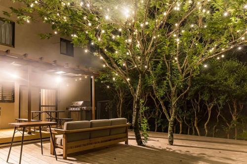 a patio with a couch and a tree with lights at Ise Shima Moritoumi in Shima