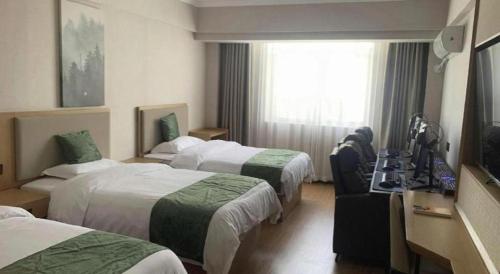 a hotel room with three beds and a television at GreenTree Inn Luoyang Henan University of Science and Technology in Luoyang
