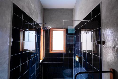a bathroom with a black tiled shower with two windows at Casa de Arte Hotel Boutique in Oaxaca City