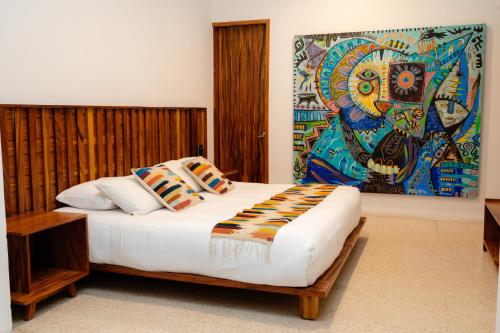 a bedroom with a bed with a painting on the wall at Casa de Arte Hotel Boutique in Oaxaca City
