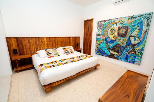 a bedroom with a bed with a painting on the wall at Casa de Arte Hotel Boutique in Oaxaca City