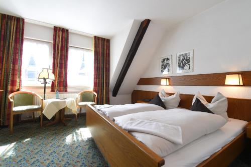a hotel room with a large bed and a table at Landhotel Gasthof Willecke in Sundern