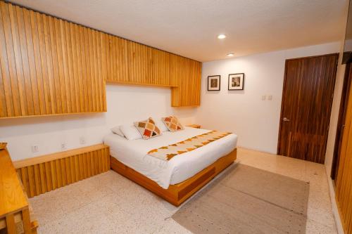 a bedroom with a bed and a wooden wall at Casa de Arte Hotel Boutique in Oaxaca City