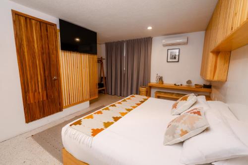 a bedroom with a large white bed and a television at Casa de Arte Hotel Boutique in Oaxaca City